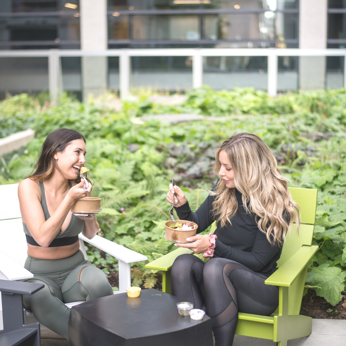 Two girls sitting at on chairs eating a prepared meal