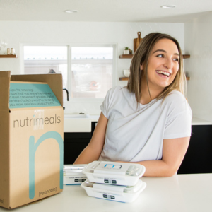 Girl leaning on counter with box of meal prep