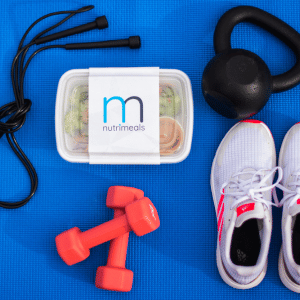 a Nutrimeal in a container on a yoga mat with running shoes, little weights and a skipping rope