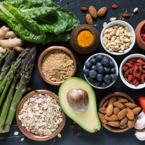 image of an avocado cut in half, almonds, berries and other immune boosting ingredients on a black table.