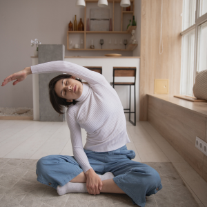 woman sitting on floor stretching with arm over her head