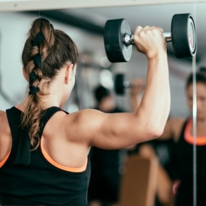 Woman shoulder pressing dumbbell weights