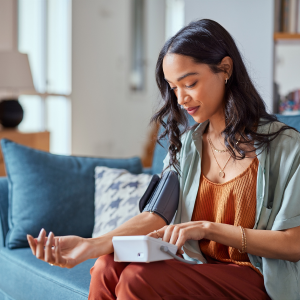 lady sitting on couch taking blood pressure reading at home