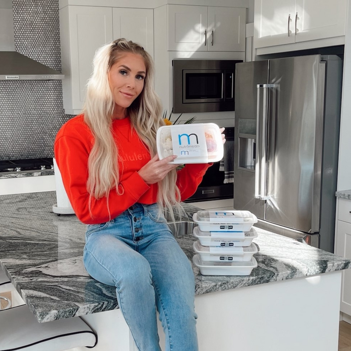 Girl sitting on counter with box of prepared meals