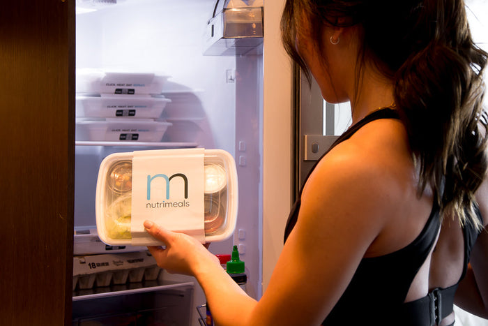 girl taking a container of gluten free meal prep out of the fridge