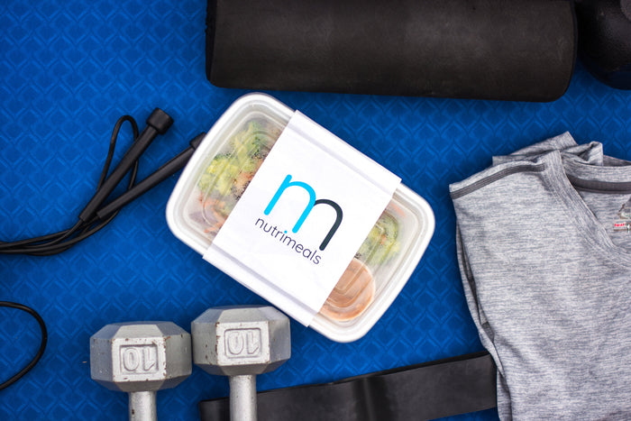Flat lay picture with a nutrimeal, weights, skipping rope and gym shirt