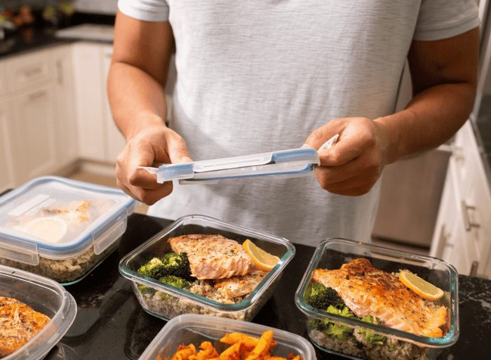 man putting a lid on his meal prep container