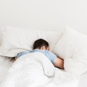 Man is sleeping with his face down in the pillows